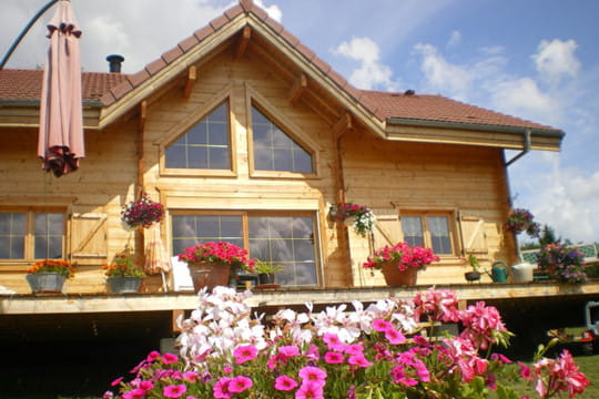 un-chalet-petit-de-bois-avec-un-toit-rouge-et-un-beau-jardin-devant-la-maison