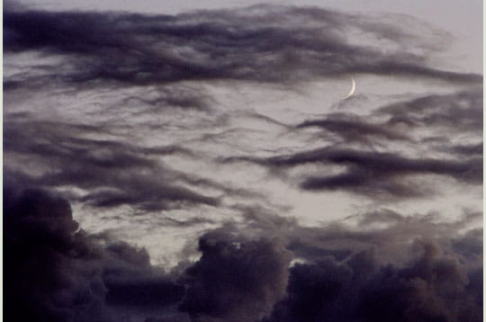 des nuages gris envahissent petit à petit le ciel. un croissant de lune parvient